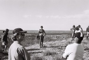 Photograph of a person holding a PA system and microphone while talking to a small group of people.